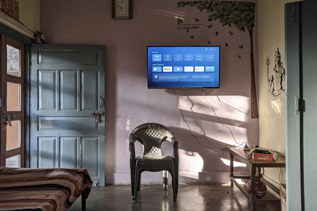 Salón soleado con televisor moderno de pared y muebles de madera