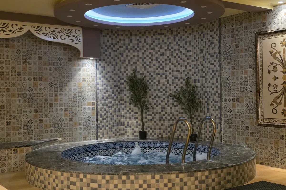 Spa interior con un jacuzzi revestido de mosaico e iluminación ambiental