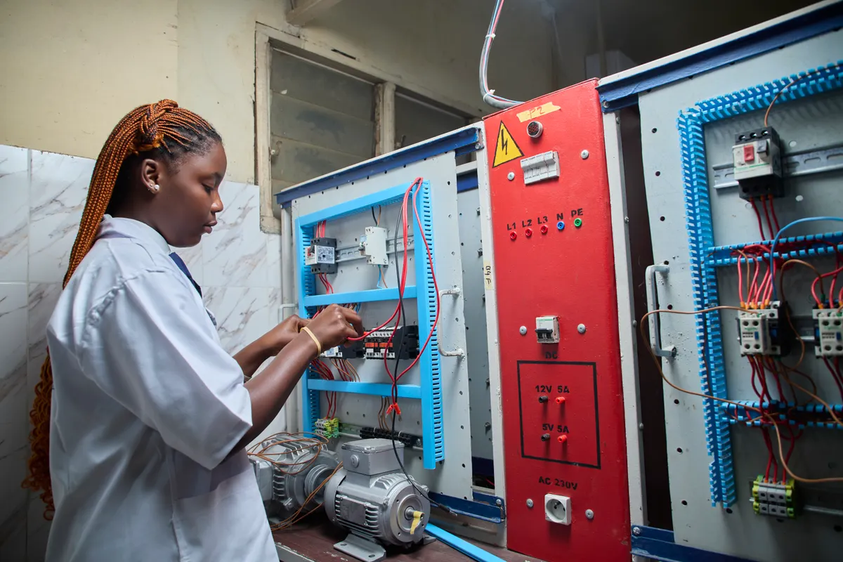 Técnica joven reparando un cuadro de control eléctrico en un entorno industrial