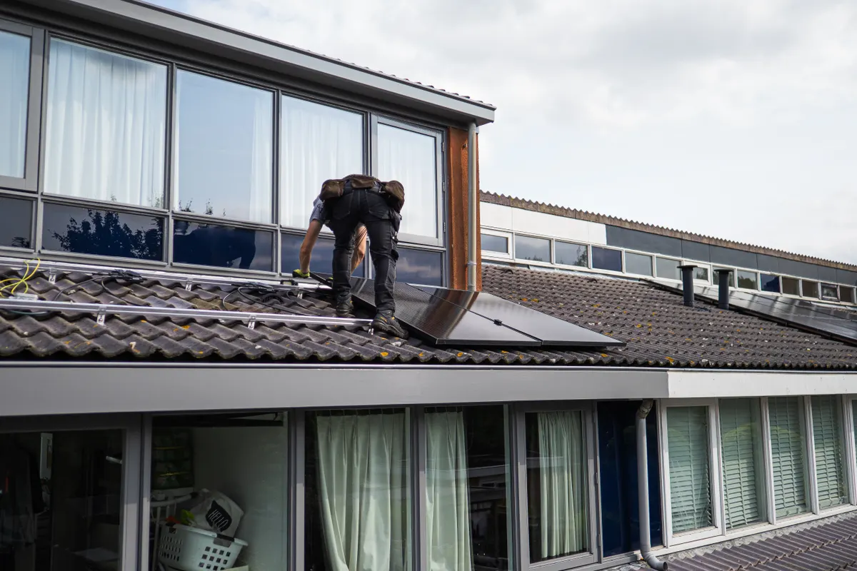 Técnico instalando paneles solares en el tejado de una vivienda durante el día