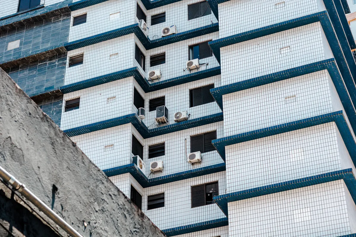 Vista abstracta de la fachada alicatada de un edificio alto con varios aires acondicionados