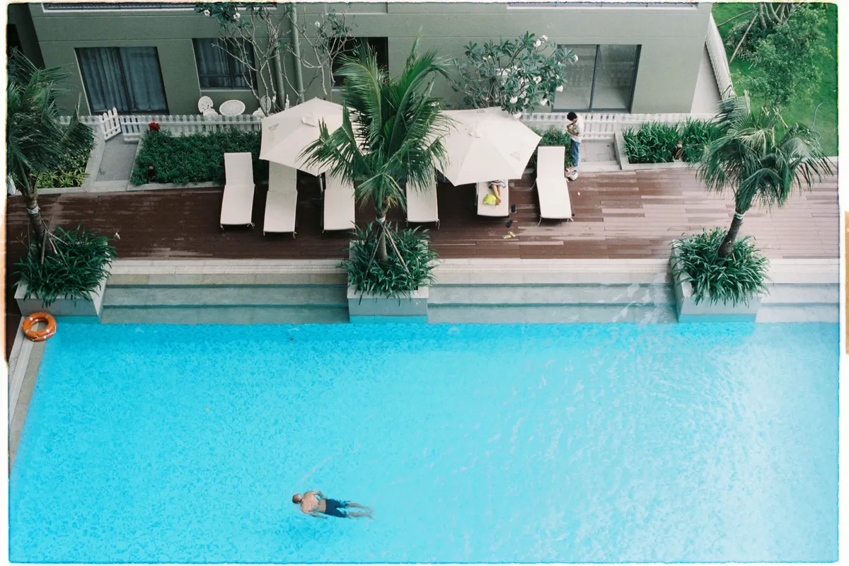 Vista aérea de una piscina con zona de tumbonas y palmeras