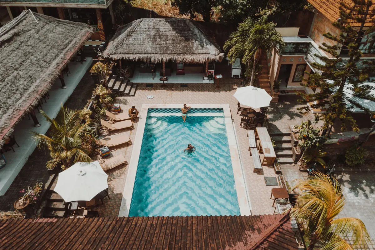 Vista aérea de una piscina rodeada de villas y palmeras