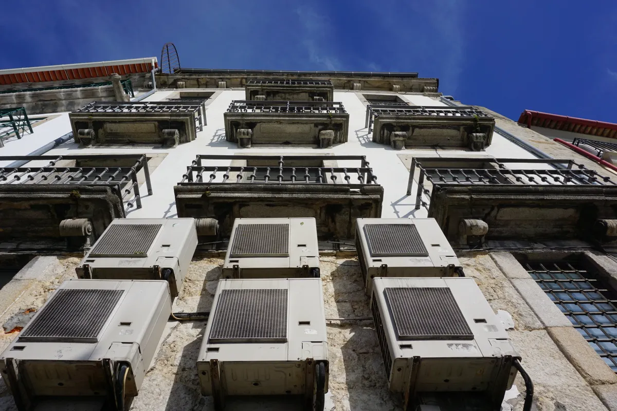 Vista desde abajo de una fachada con balcones y aparatos de aire acondicionado