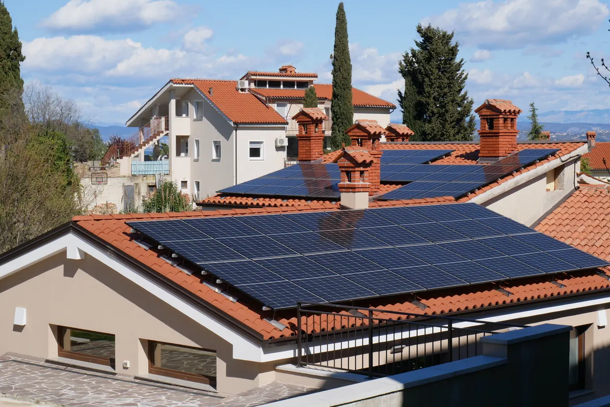Vista panorámica de placas solares en tejados de teja roja de un barrio residencial soleado